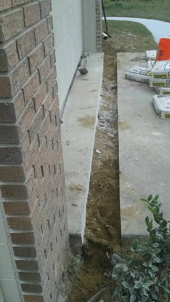 Concrete driveway trench cut drainage pipe sakrete bags brick garage, Sanford